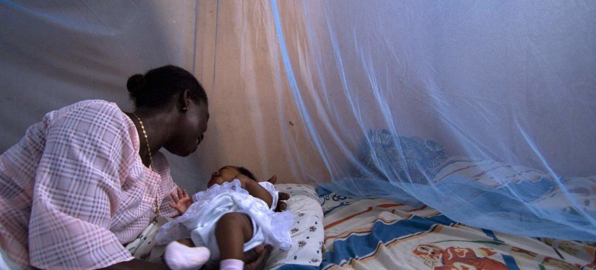 Infant in Ghana protected from malaria by a bednet. 